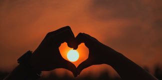 hands held in heart shape around sun in distance - photo by Shera Banerjee on Pexels