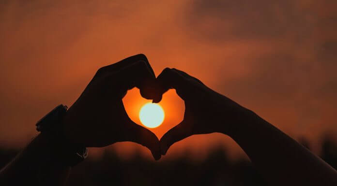 hands held in heart shape around sun in distance - photo by Shera Banerjee on Pexels