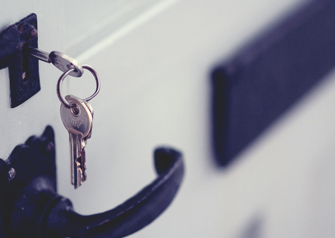 silver keys in lock - black hardware on white door - photo by Jaye Haych on Unsplash