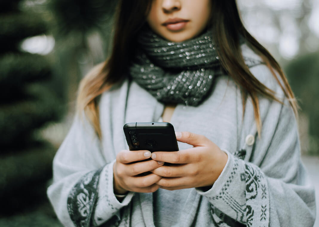 young woman wearing scarf and texting on smartphone - photo by Miguelangel Perez on Unsplash