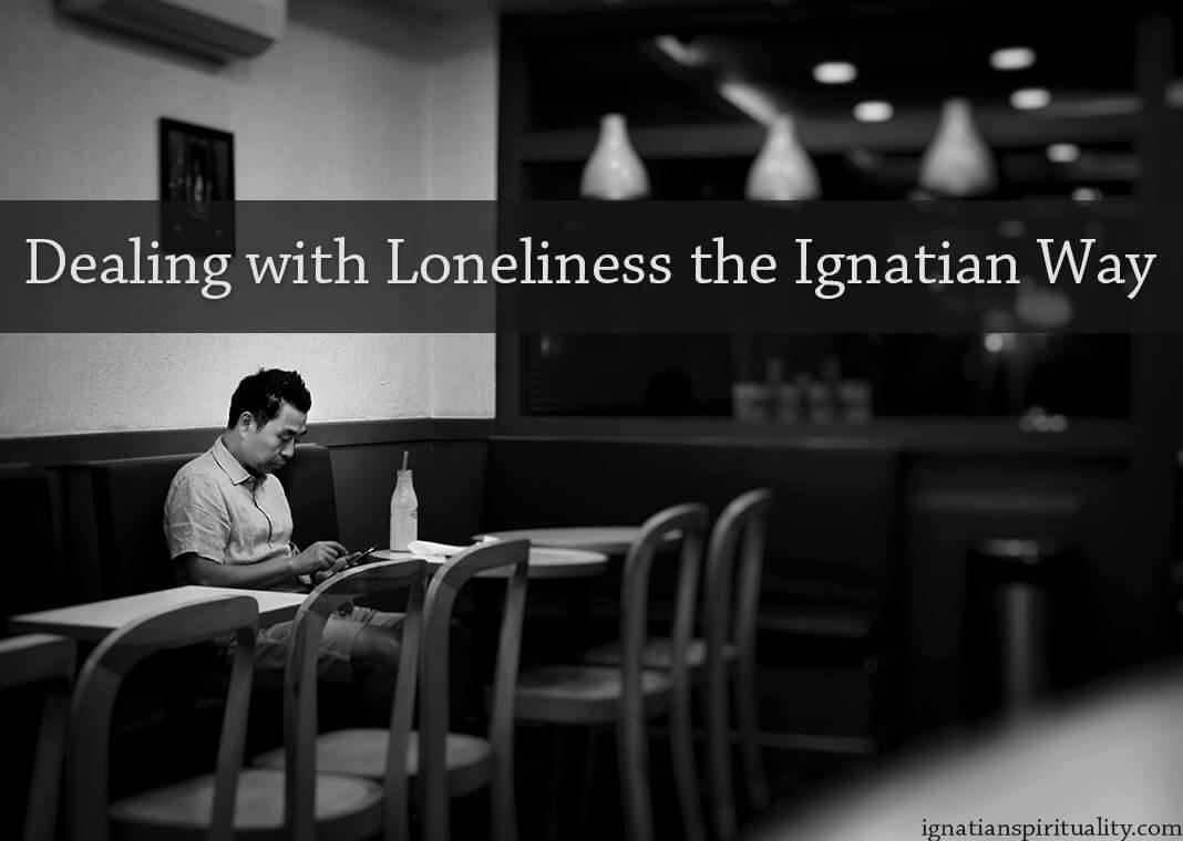 Dealing with Loneliness the Ignatian Way - text over image of man alone in restaurant - photo by Chetan Hireholi on Unsplash