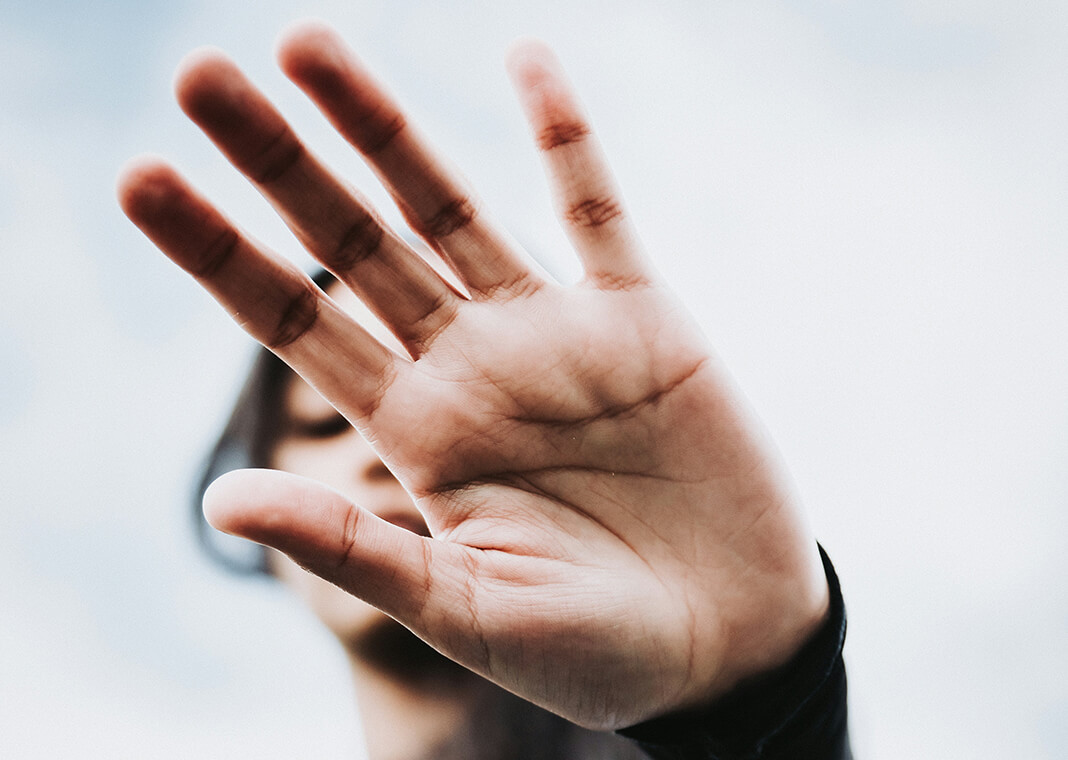 young woman holding her hand in front of camera to cover her face - photo by Luwadlin Bosman on Unsplash