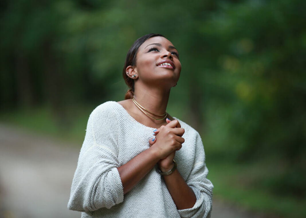 young woman praying - Kosim Shukurov/Shutterstock.com
