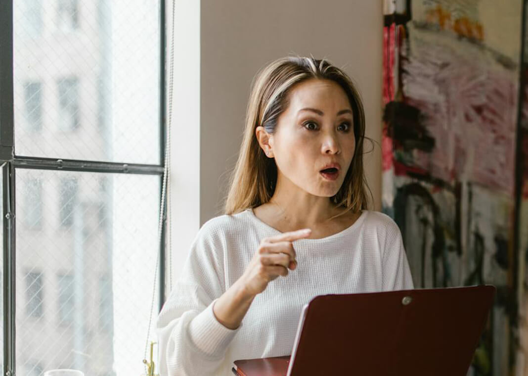 woman near window holding laptop and speaking - photo by RDNE Stock project on Pexels.com