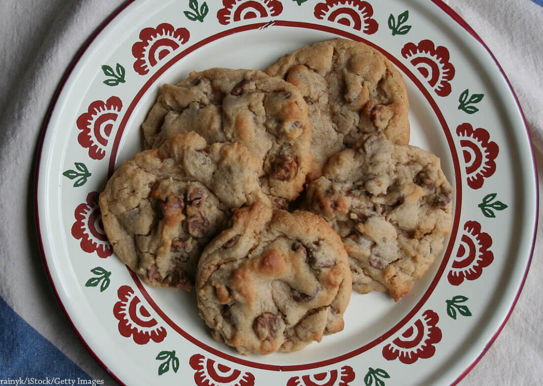 chocolate-chip cookies on a plate edged with red floral design - rainyk/iStock/Getty Images