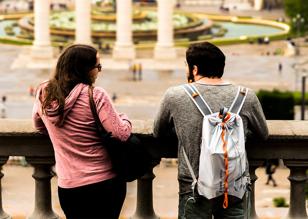 man with backpack and woman in pink shirt standing together in friendship - photo by Djim Loic on Unsplash