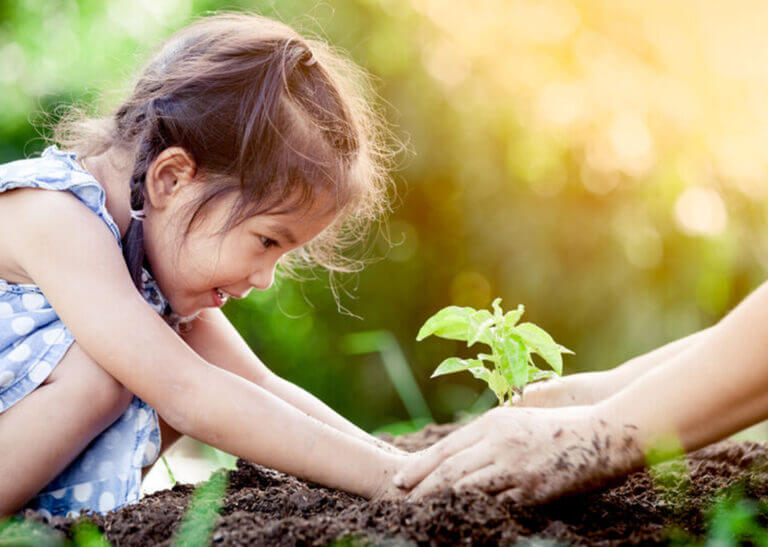 young girl planting a tree with adult's help - A3pfamily/Shutterstock.com