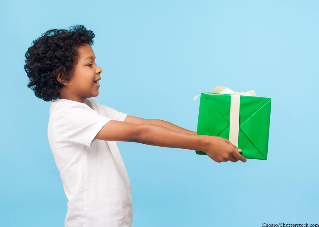 child holding gift out to unseen recipient - Khosro/Shutterstock.com